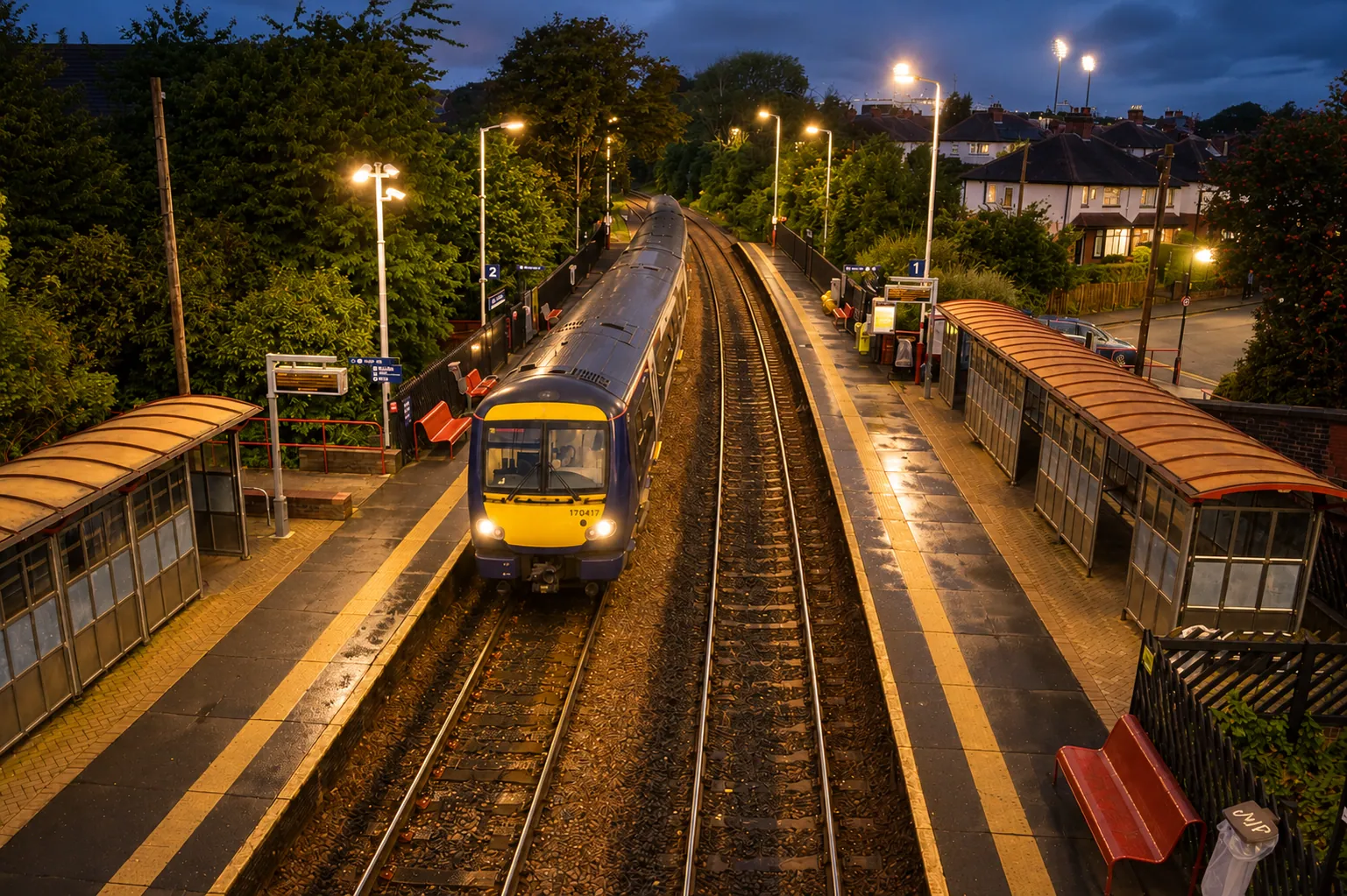 Burley Park railway station at dusk with a train at the platform, beside the terraced streets between Kirkstall Lane and Burley Road, Leeds