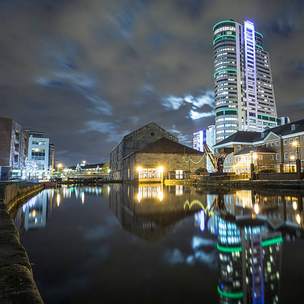 Leeds city centre waterfront at night with Bridgewater Place and warehouse conversions reflected in the dock